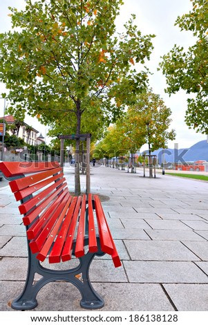Red bench on neat and clean pedestrian sidewalk in Italy