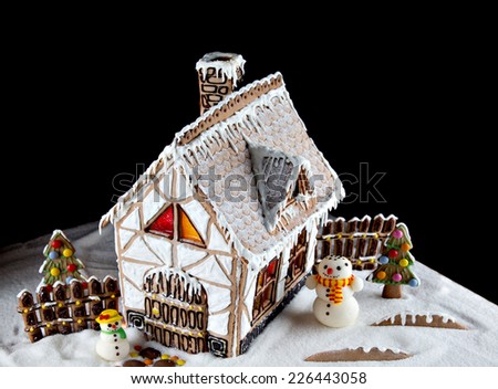Decorative gingerbread house with lights inside on black background. Rural Christmas night scene