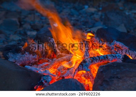 Classic camping campfire in rock fire ring at dusk closeup
