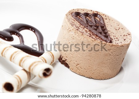 Chocolate mousse on plate decorated with two cookie sticks. On white plate