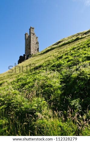 Dunstanburgh Castle tower / Iconic Dunstanburgh castle ruin built in the 14th century viewed from below the tower