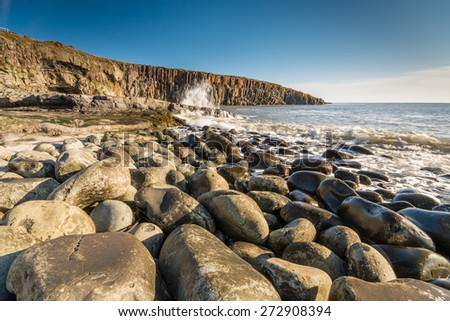 Rocky shore at Cullernose Point / Waves crashing against the rocks at Cullernose Point with sea washed boulders in the foreground