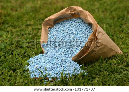 Blue fertilizer in brown paper bag on green grass