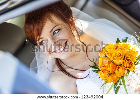 Young happy bride with yellow rose siting in the car.