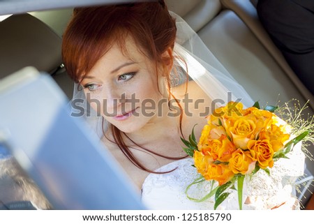 Young happy bride with yellow rose siting in the car.