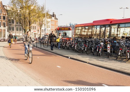 AMSTERDAM, NETHERLANDS - APRIL 22: People go to work by bicycles and buses  on april 22, 2013 in Amsterdam. In Capital of Netherlands are also twice as many bikes then cars.