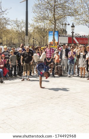 PARIS, FRANCE -  APRIL 25: B-boy doing some breakdance moves in front a street crowd, at Arch of Triumph on April 25, 2013 in Paris. Its popular form of earnings in big cities.