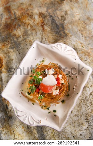 Presentation in flat nest of spaghetti sauce full of scallops