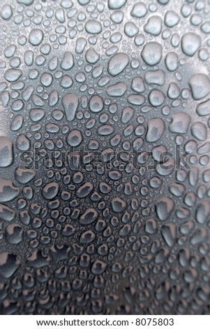 Close up of rain drops beaded up on a car hood