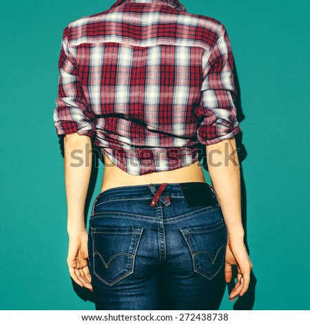 Model girl in checkered Shirt and Blue jeans on green background from the back
