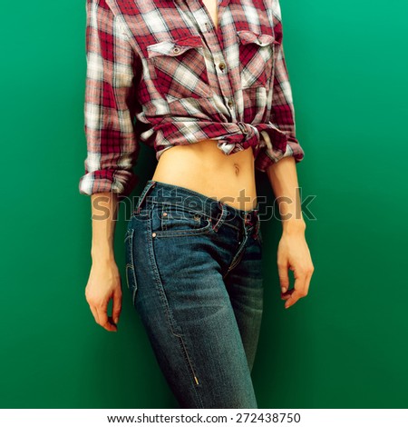 Girl in checkered Shirt and Blue Jeans on green background