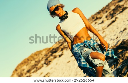 Stylish Model in the Desert in fashionable torn Jeans and  checkered Shirt.