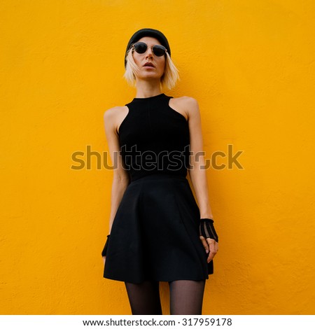 Stylish Girl in black at the yellow wall .Urban fashion style