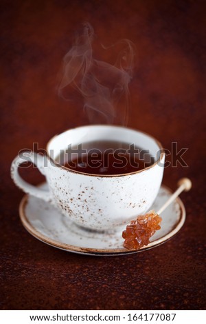 Cup of hot tea and rock candy sugar stick, selective focus