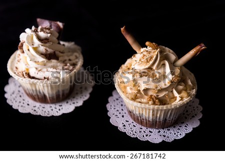 Two Chocolate Cupcakes with walnut and chocolate on black background