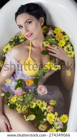 Brunet girl in bath with flowers