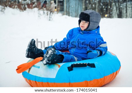 A boy having fun riding a snow tube