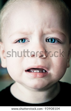 Baby boy crying with blue eyes full of tears close up portrait