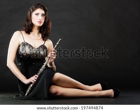 Art and artist. Portrait of woman girl flutist flautist performer playing flute musical instrument on black. Classical music.