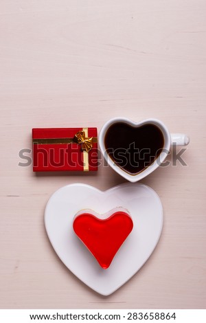 Heart shaped coffee cup jelly cake and red gift box on wooden surface, top view copy space for text