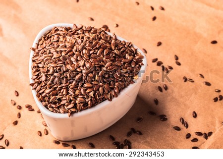 Healthy food diet. Brown flax seeds linseed in white bowl on paper background