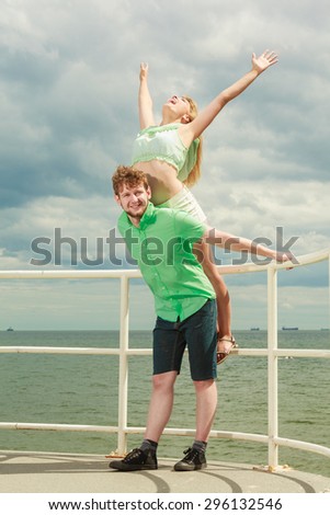 Summer happiness concept. Woman and man young couple in love playing sharing free time having fun outdoor on sea pier sky background