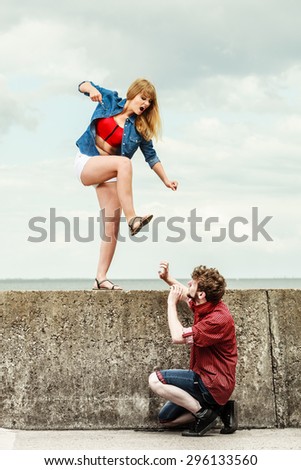 Relationship concept. Woman and man young couple in love playing fighting, angry fury girlfriend screaming outdoor on sky background