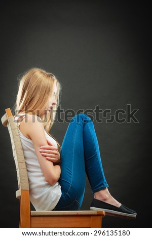 Loneliness negative emotion concept. Young sad lonely woman sitting huddled on chair
