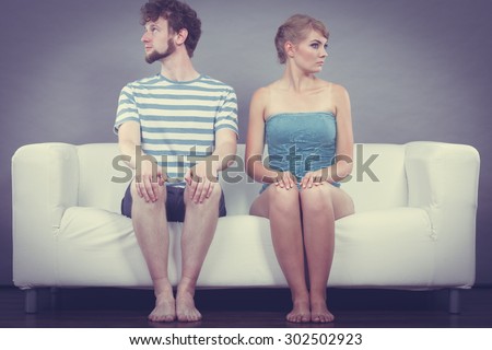 Bad relationship concept. Man and woman in disagreement. Young couple after quarrel sitting offended on couch at home
