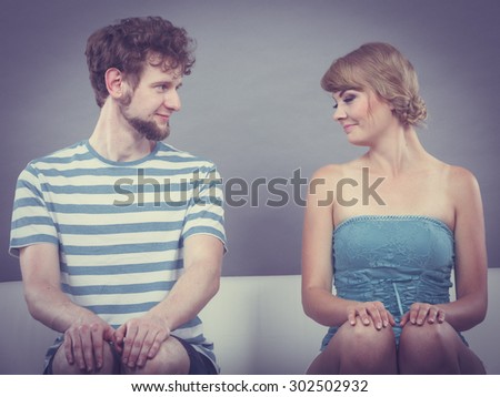 Relationship concept. Shy woman and man sitting close to each other on the couch.
