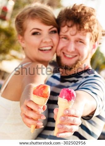 Summer holidays and happiness concept. Young couple eating ice cream outdoor in the city