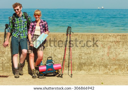 Adventure, summer, tourism active lifestyle. Young couple backpacker looking at map by seaside, plan their sightseeing