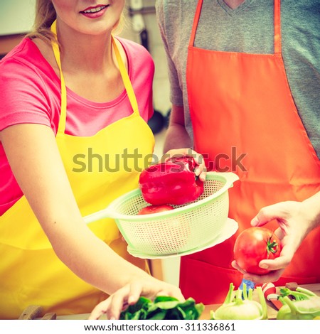 Healthy eating, vegetarian food, cooking, dieting and people concept Happy young couple woman and man having fun in kitchen at home preparing fresh vegetables salad