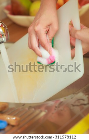 Household. Closeup woman doing the washing up in kitchen cleaning plastic cutting board