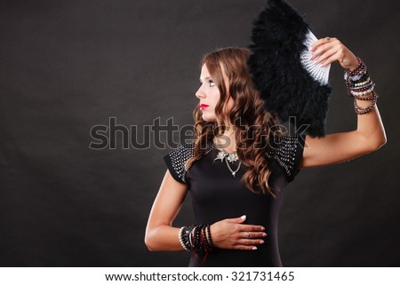 Portrait of beautiful brunette woman with black feather fan in hand