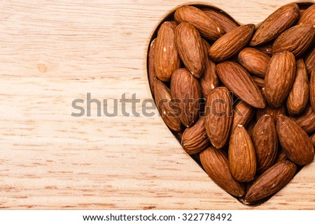 Whole food, good for health. Heart shaped almonds on wooden surface board background