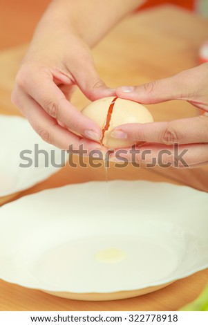 Woman hands with egg in a kitchen, cracking eggs close up