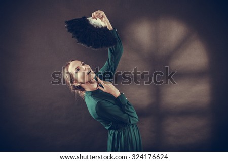 Vintage woman retro style dancing with black feather fan on dark