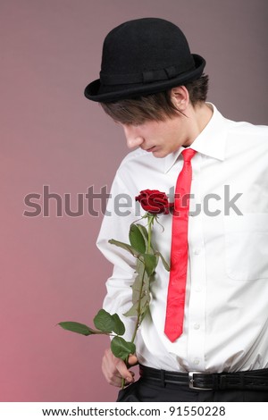 Young men with the red rose on colour background. Love and reflection.