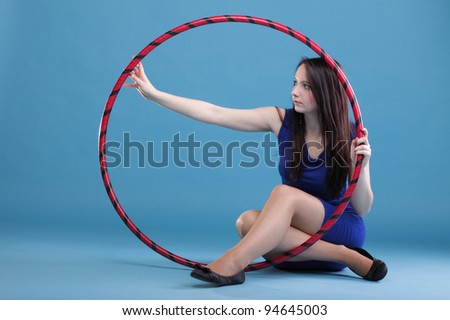 Beautiful woman in a sport wear. Dance hoop gym exercises blue background