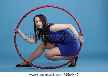Beautiful woman in a sport wear. Dance hoop gym exercises blue background