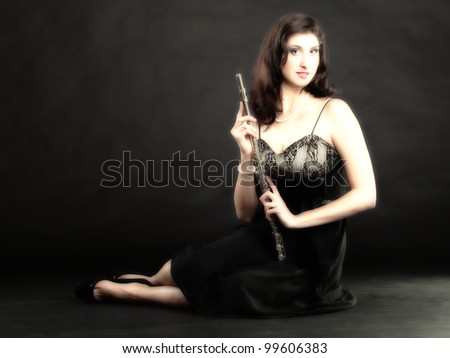 girl woman plays the flute on a black background