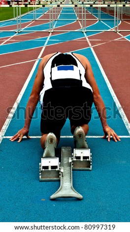 Man in a start block on an athletic track