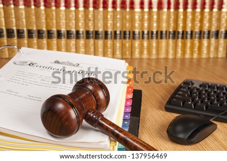 Justice gavel on certificate of title with legal books and computer keyboard in the background
