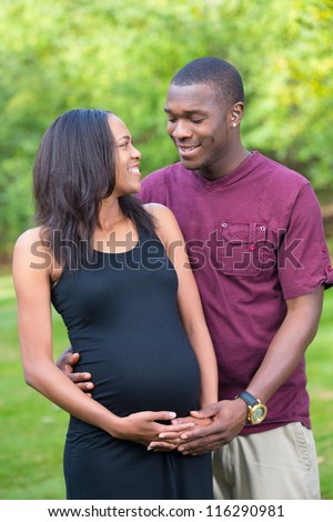 Black Couple Expecting Pregnancy Woman Hugging and Kissing Outdoor