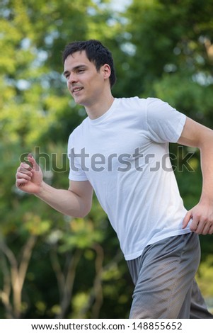Healthy Looking Young Man Jogging in the Woods Under Morning Sunlight