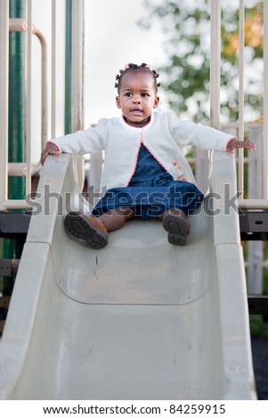 3-year old African American Girl Playing on slide in the Playground