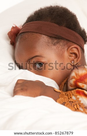 3 year old African American girl in colorful costume playing hide seek
