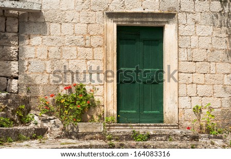 The facade of an old rustic building with a green door