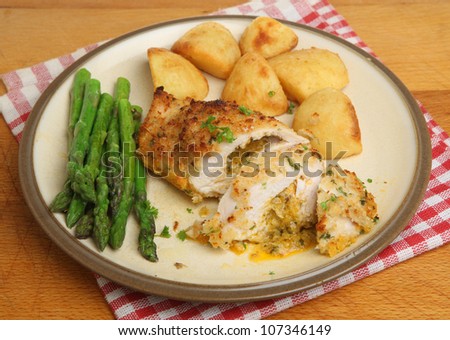Chicken Kiev, stuffed with garlic and herb butter, served with potatoes and asparagus.